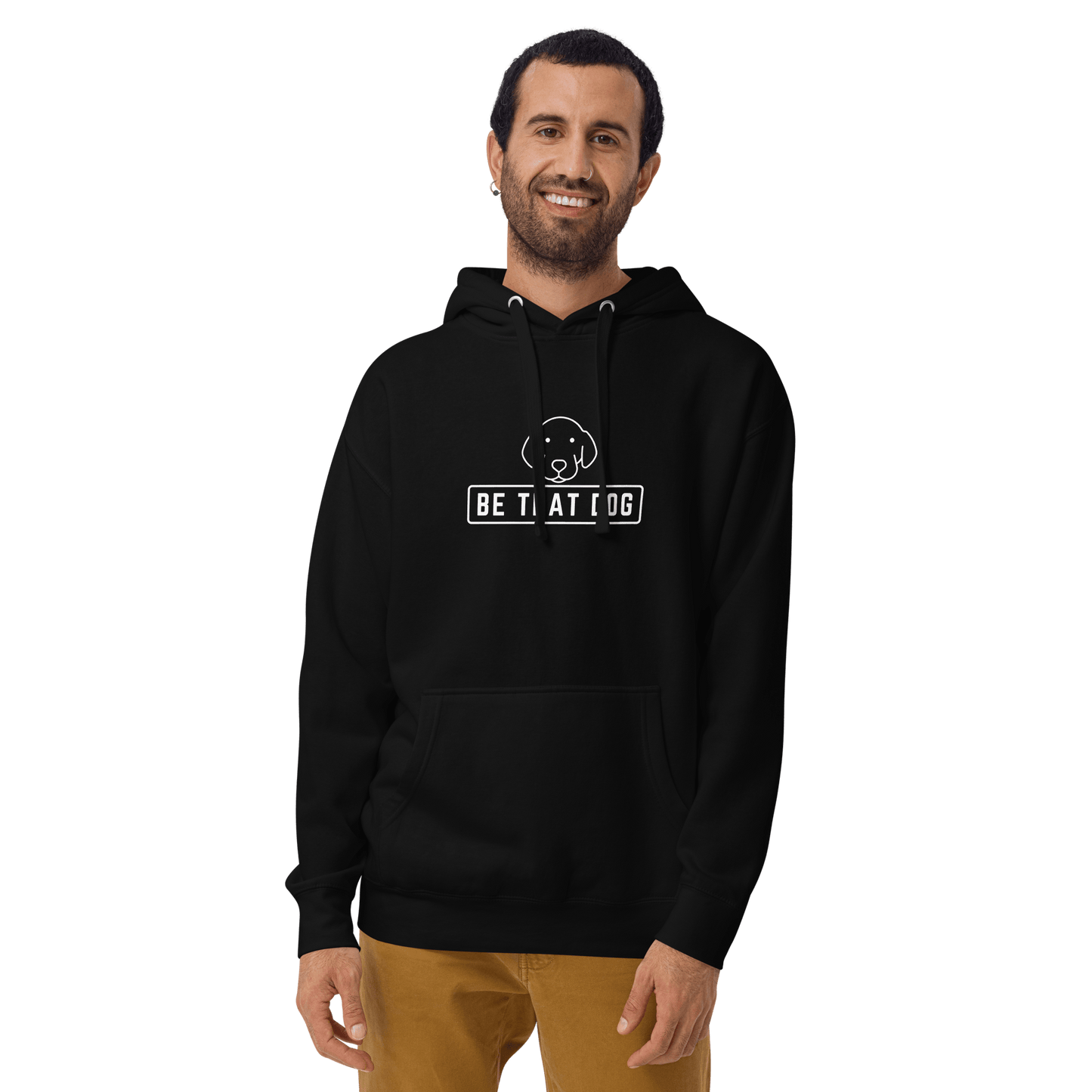 A man smiles in the THiNK LiKE A DOG® Be THAT Dog Minimalist Hoodie—an ultra-soft, black sweatshirt with a dog design and "BE THAT DOG" logo—paired with khaki pants, perfect for any dog lover.