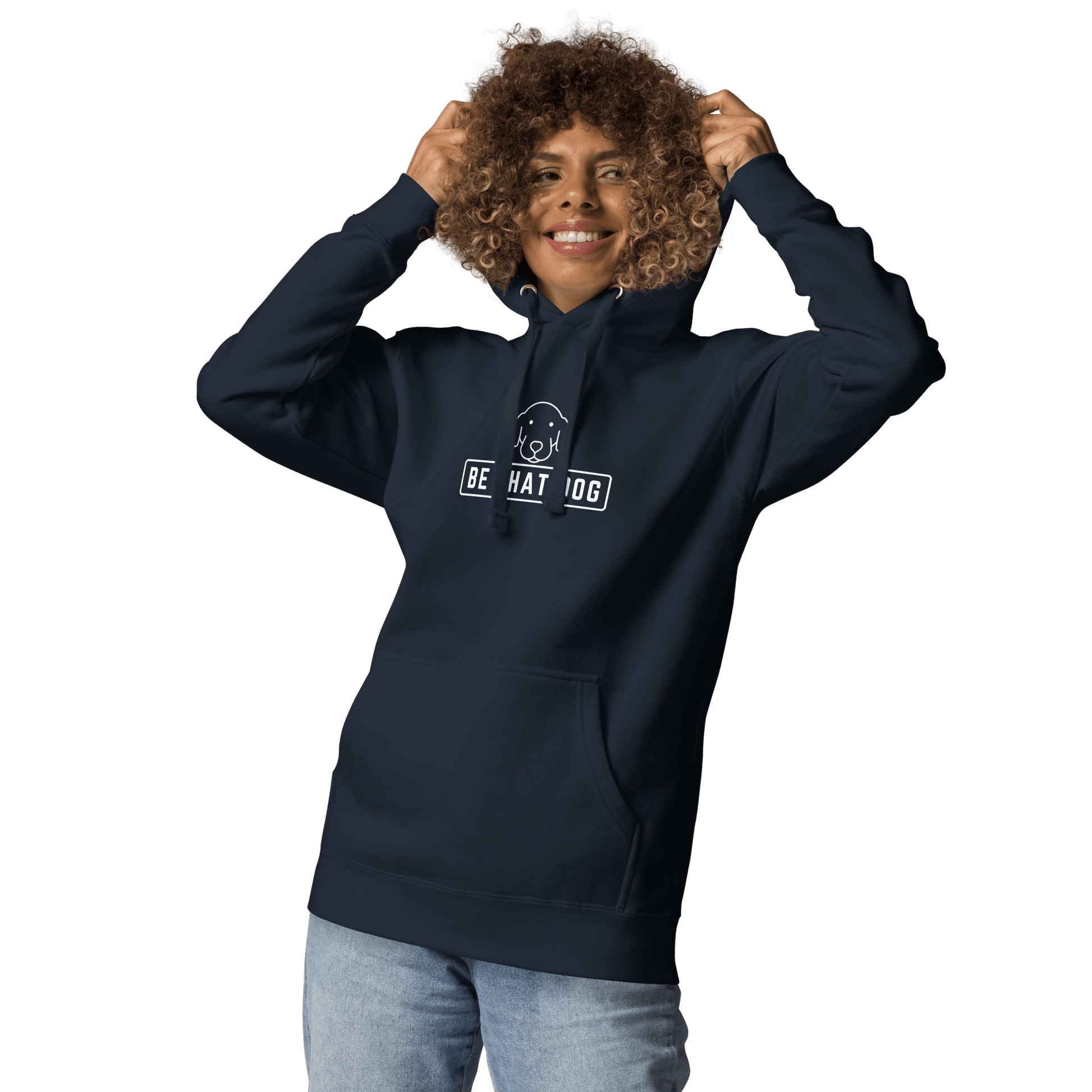 A person grins in a navy THiNK LiKE A DOG® "Be THAT Dog Minimalist Hoodie – Sleek & Cozy Dog Lover Sweatshirt," adjusting the hood. The ultra-soft fabric gleams against the black, showcasing this dog lover's essential design.