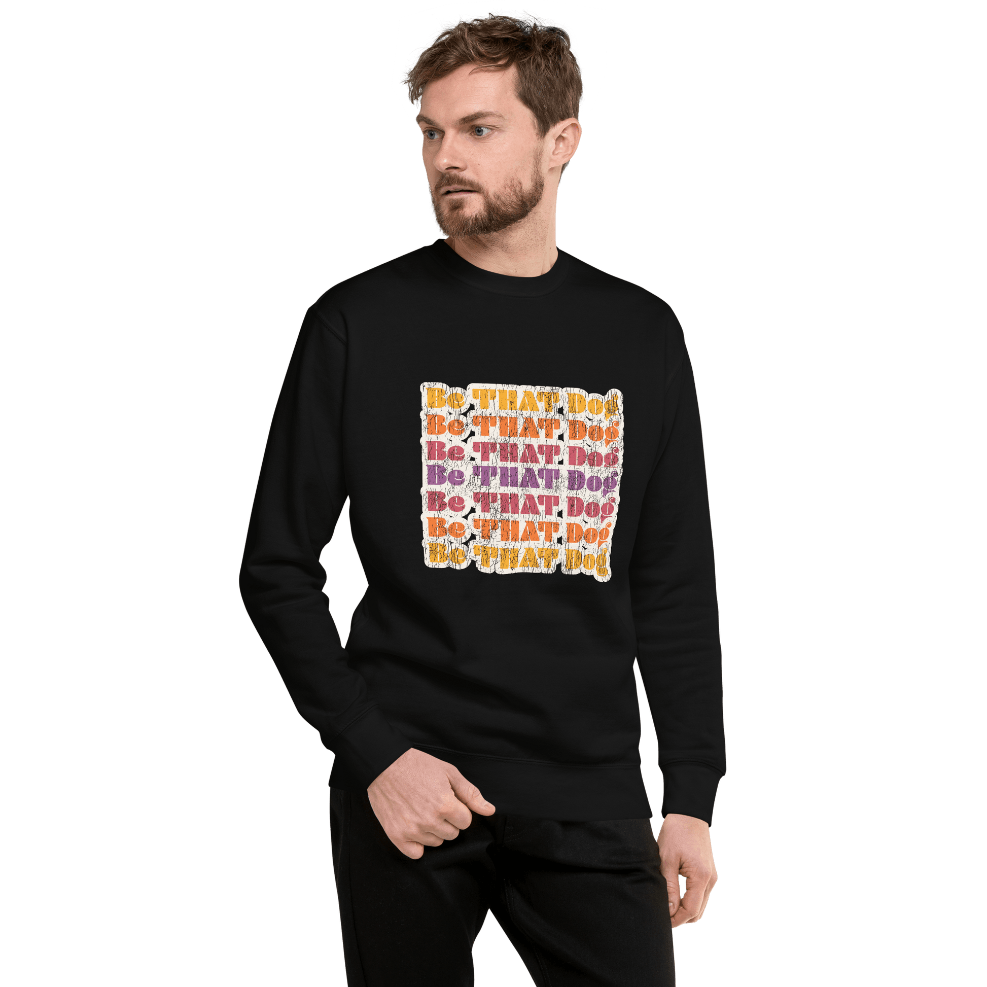 A man wears a black THiNK LiKE A DOG® "Be THAT Dog Retro Sweatshirt," featuring colorful '70s-style text, as he looks left against a plain background.
