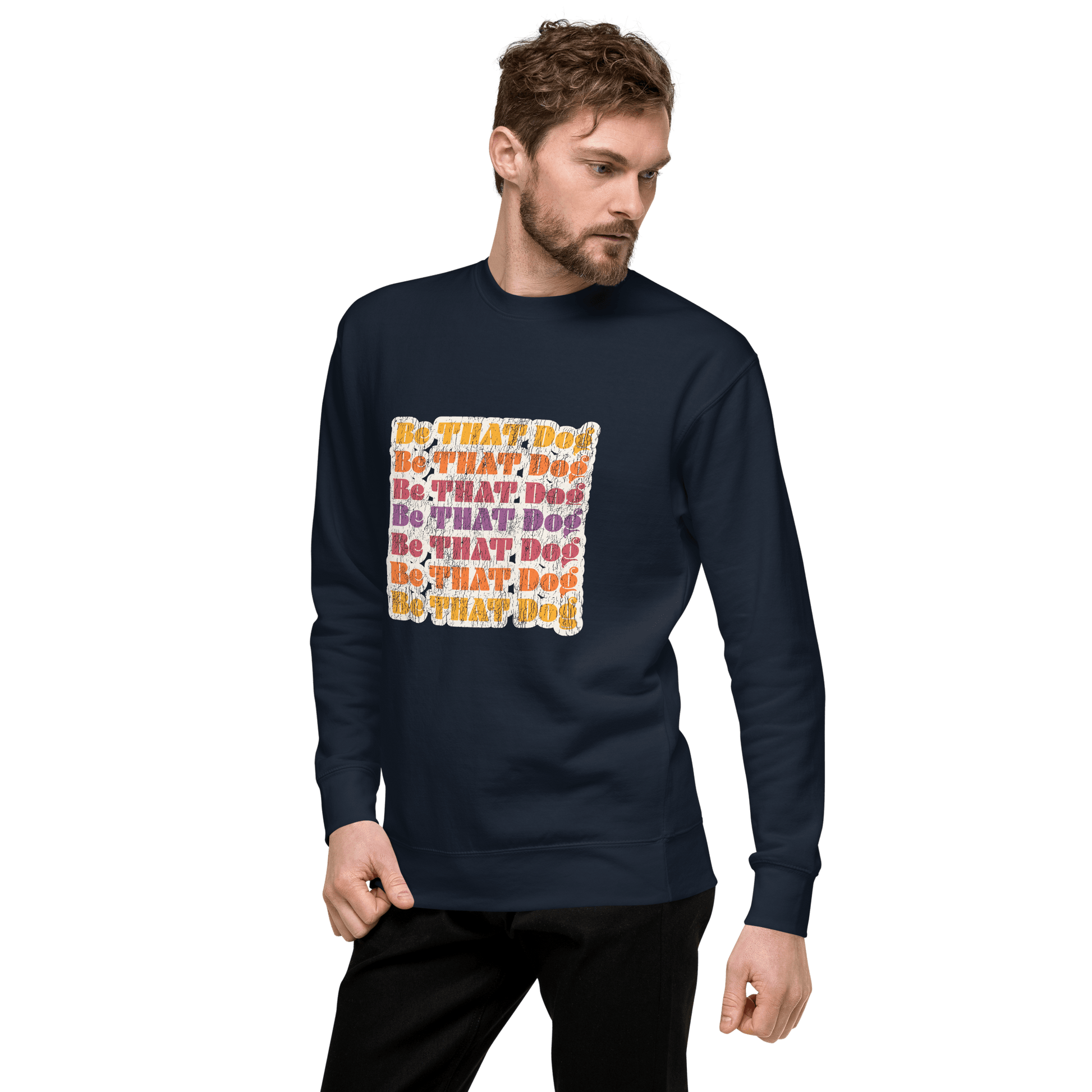 A man wearing a THiNK LiKE A DOG® 'Be THAT Dog Retro Sweatshirt – ‘70s Style Unisex Dog Lover Sweater' stands against a black background, featuring colorful text graphics on the front.
