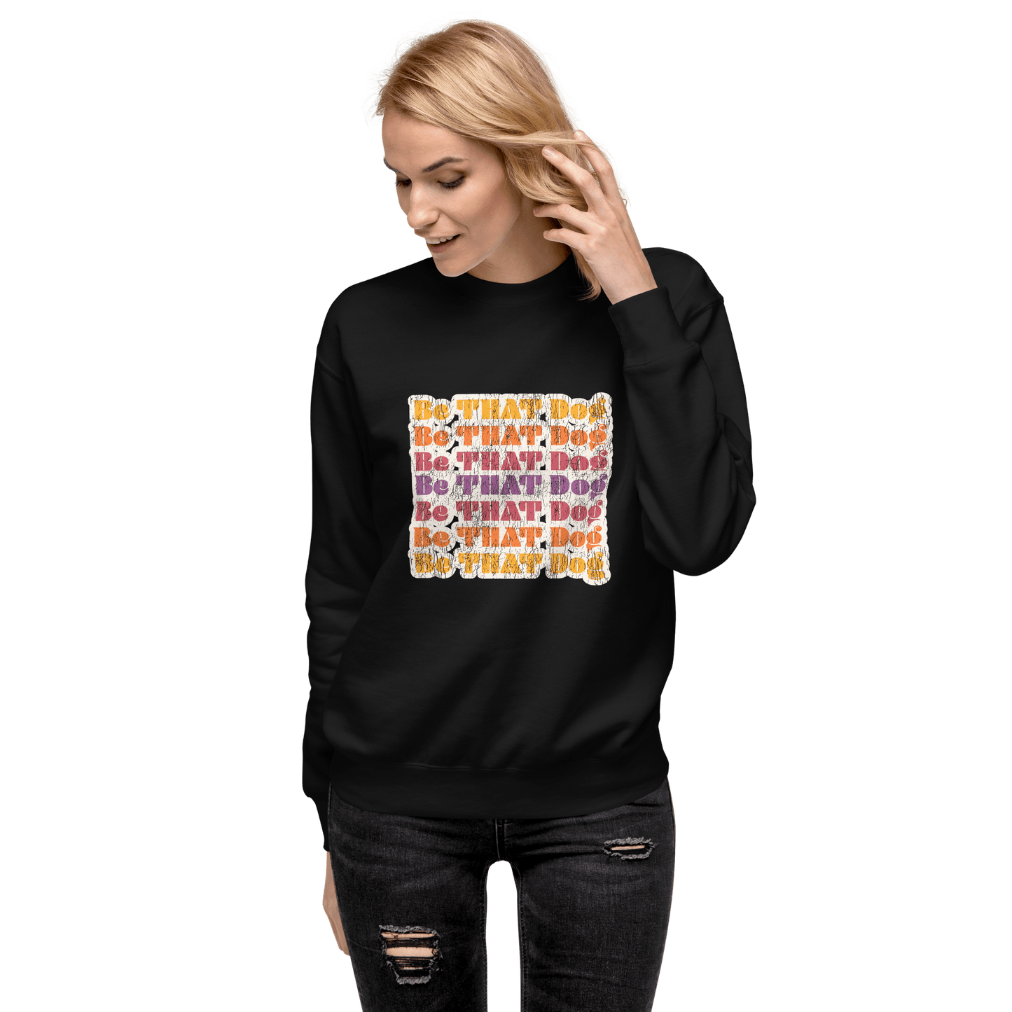 A person is wearing a Be THAT Dog Retro Sweatshirt by THiNK LiKE A DOG®, featuring the colorful 'BE THAT DOG' text pattern on black, capturing ‘70s vintage vibes.