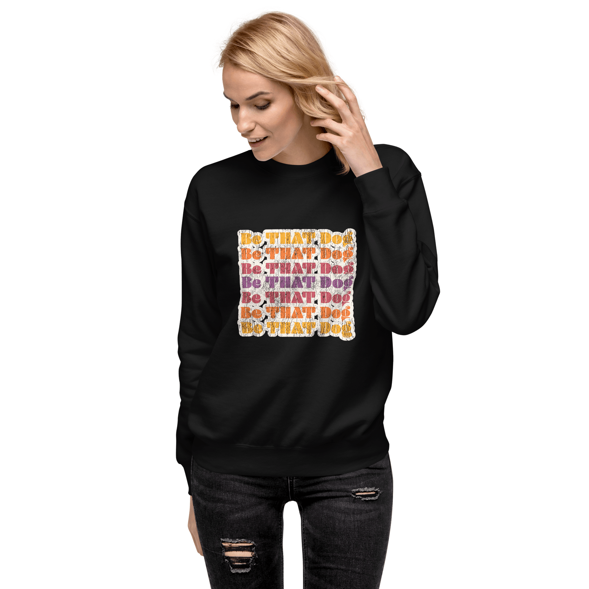 A person is wearing a Be THAT Dog Retro Sweatshirt by THiNK LiKE A DOG®, featuring the colorful 'BE THAT DOG' text pattern on black, capturing ‘70s vintage vibes.