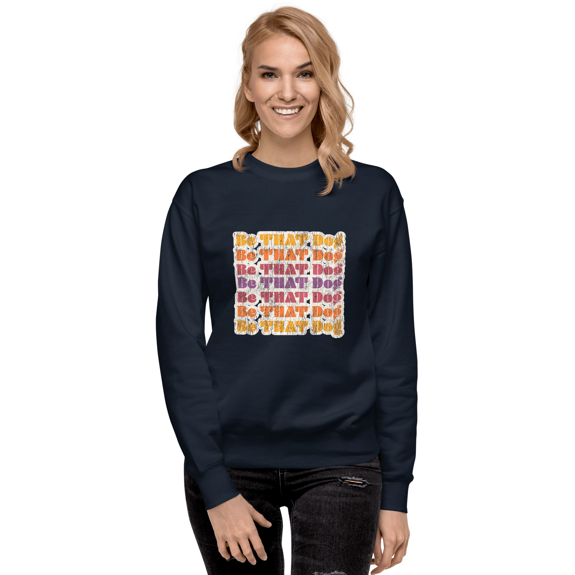 A smiling person wears the Be THAT Dog Retro Sweatshirt by THiNK LiKE A DOG®, featuring navy fabric with multicolored "Be That Dog" text—a must-have '70s style unisex sweater for dog lovers.