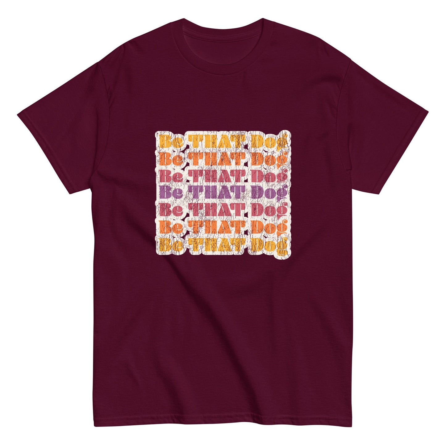 The THiNK LiKE A DOG® "Be That Dog Retro Unisex Tee" is a maroon shirt with a '70s-inspired design featuring vibrant orange and purple "Be THAT Dog" text in a square formation.