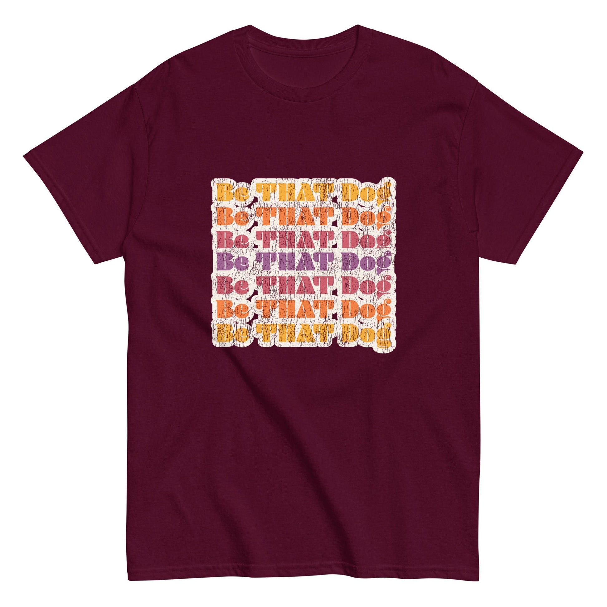 The THiNK LiKE A DOG® "Be That Dog Retro Unisex Tee" is a maroon shirt with a '70s-inspired design featuring vibrant orange and purple "Be THAT Dog" text in a square formation.