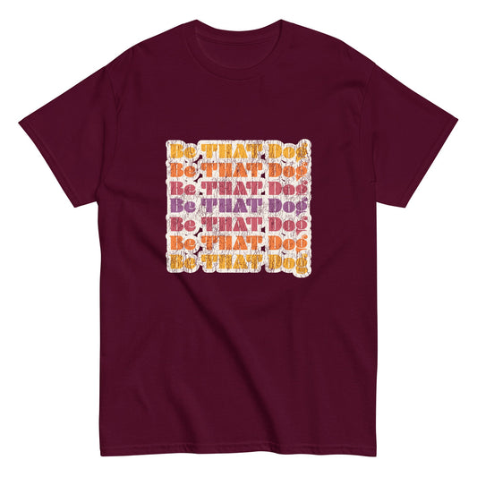 The THiNK LiKE A DOG® "Be That Dog Retro Unisex Tee" is a maroon shirt with a '70s-inspired design featuring vibrant orange and purple "Be THAT Dog" text in a square formation.