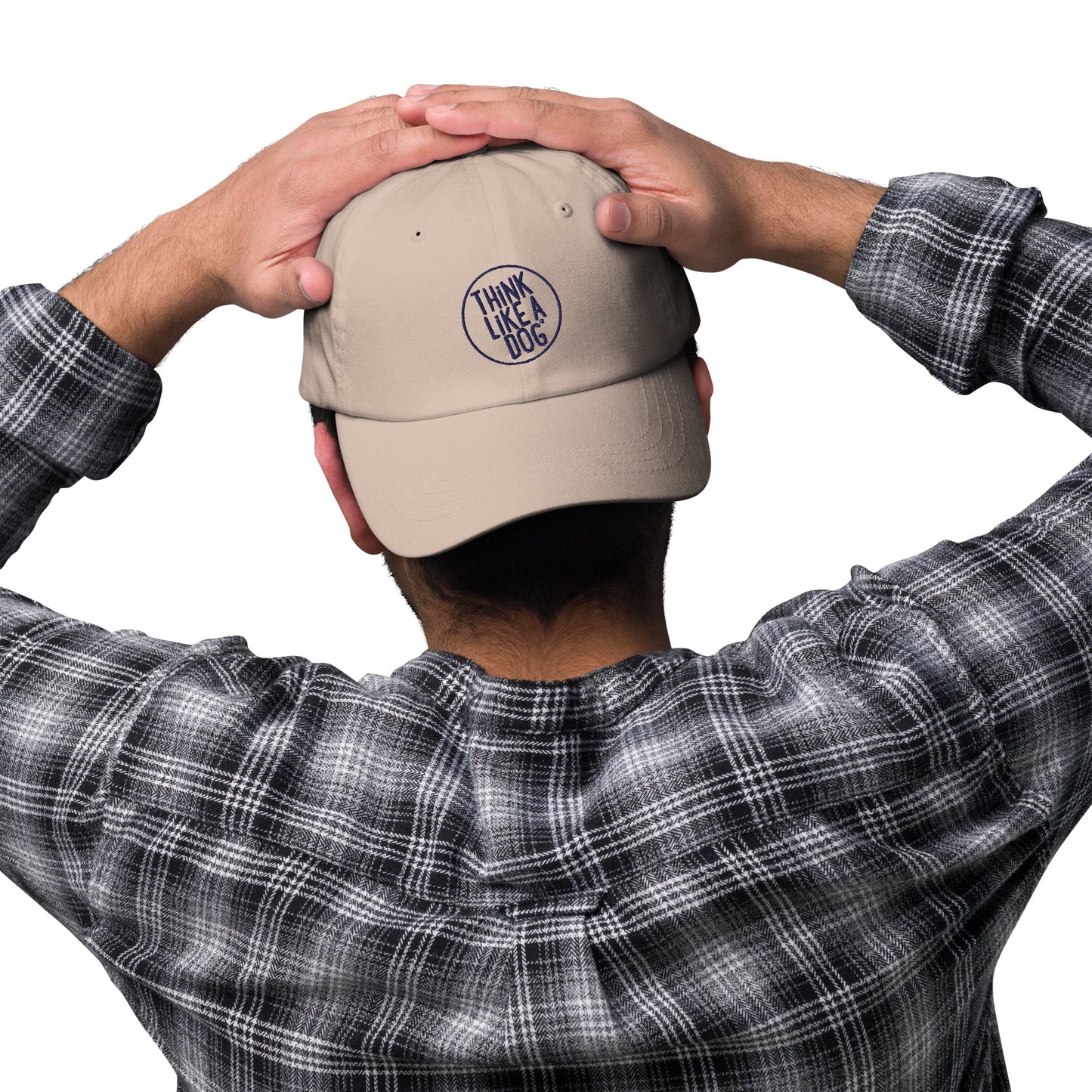 A person wearing a Classic Navy Dad Hat - Think Like a Dog Circle Logo from THiNK LiKE A DOG®, and a checkered shirt, is seen from behind, hands resting on the back of their head.