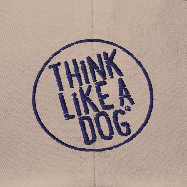 The Classic Navy Dad Hat from THiNK LiKE A DOG® showcases a beige fabric surface adorned with the Think Like a Dog Circle Logo, featuring blue capital letters, making it an ideal choice for hat enthusiasts and dog lovers alike.