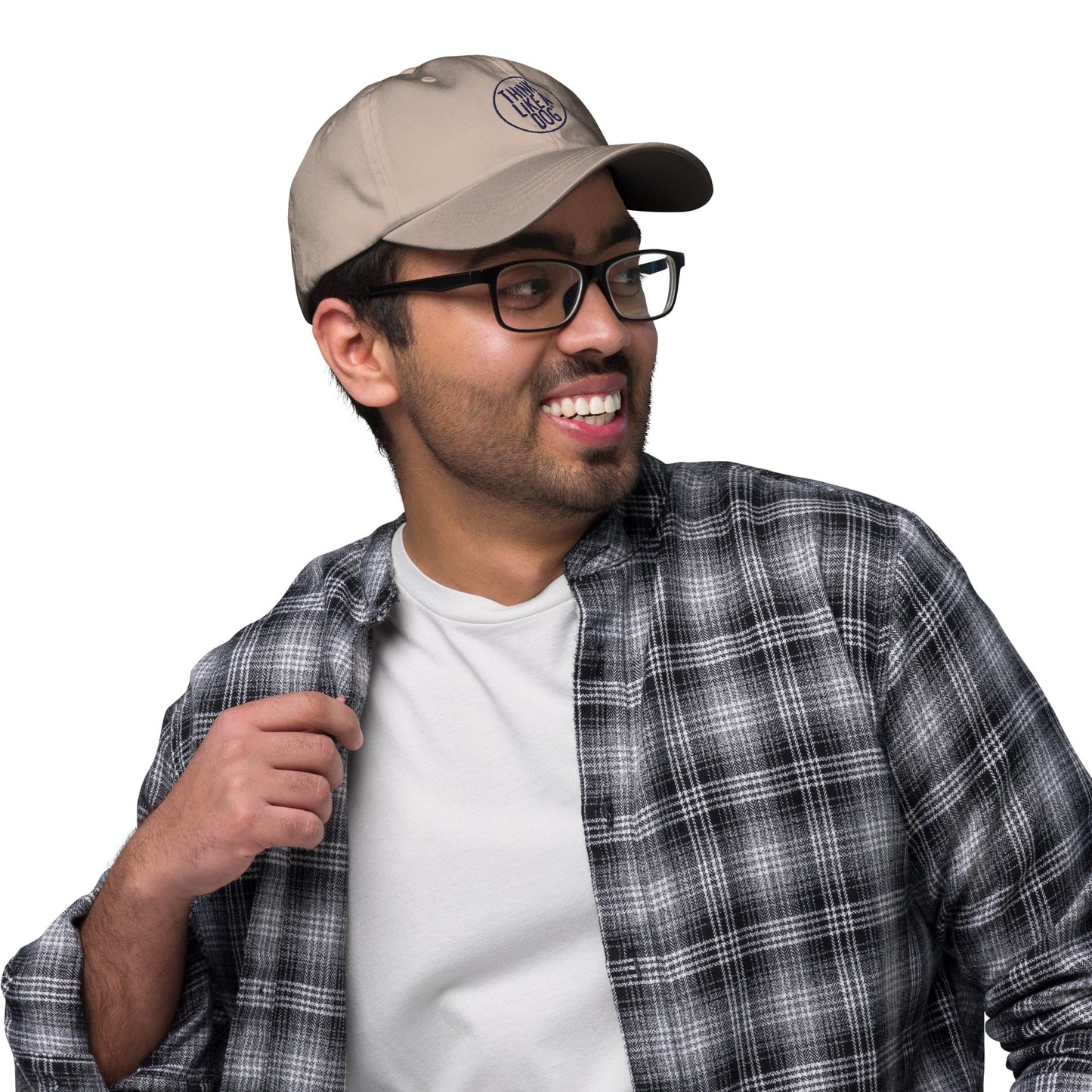A man wearing a THiNK LiKE A DOG® Classic Navy Dad Hat with the Think Like a Dog Circle Logo, black-rimmed glasses, and a black and white plaid shirt over a white t-shirt, smiles and looks to the side.