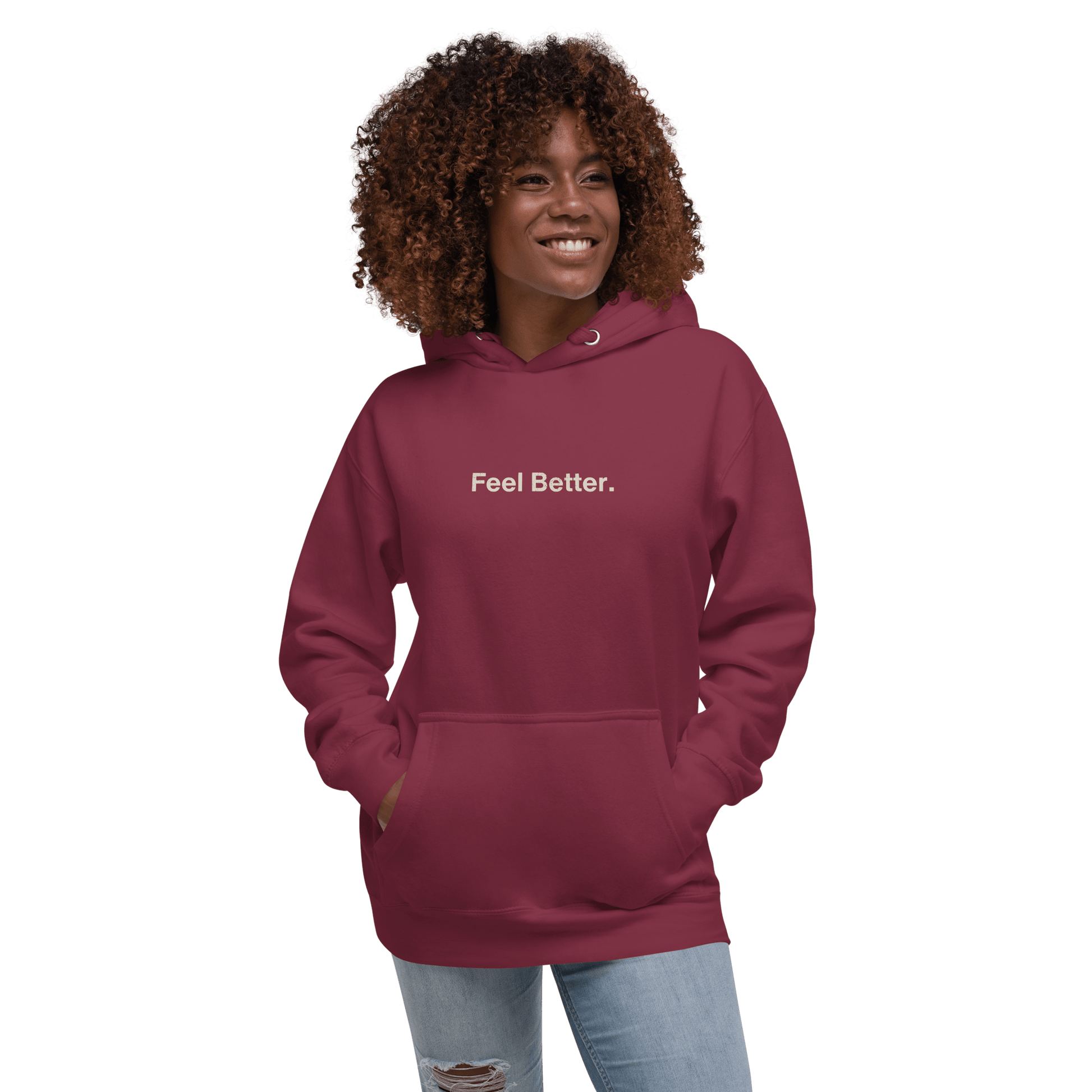 With her curly hair cascading and hands tucked in the pockets, a woman smiles in a maroon THiNK LiKE A DOG® "Feel Better Dog Lover Hoodie – Cozy Comfort for Pet Owners & Dog Moms" against a sleek black background, embodying warmth and style.