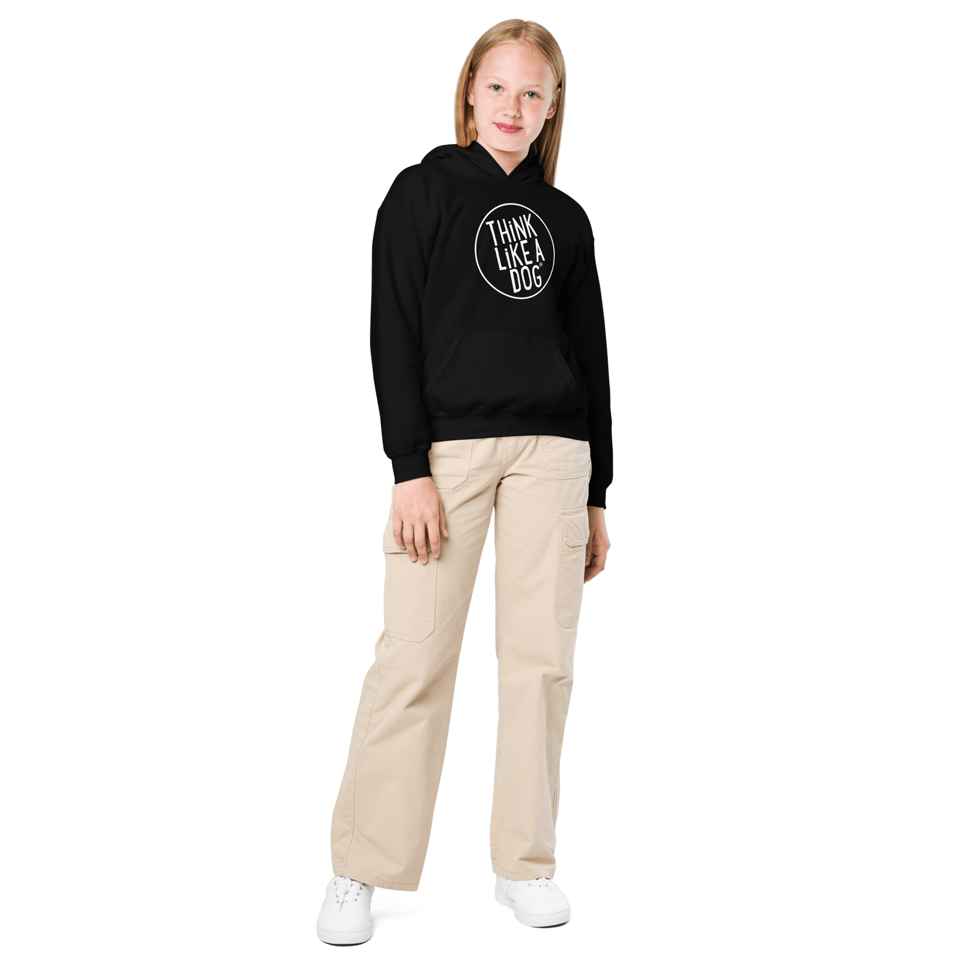 A child in a Kids Heavy Blend Hoodie with the THiNK LiKE A DOG® White Logo, beige cargo pants, and white sneakers stands against a black background, showcasing ultimate Dog-Lover Style.