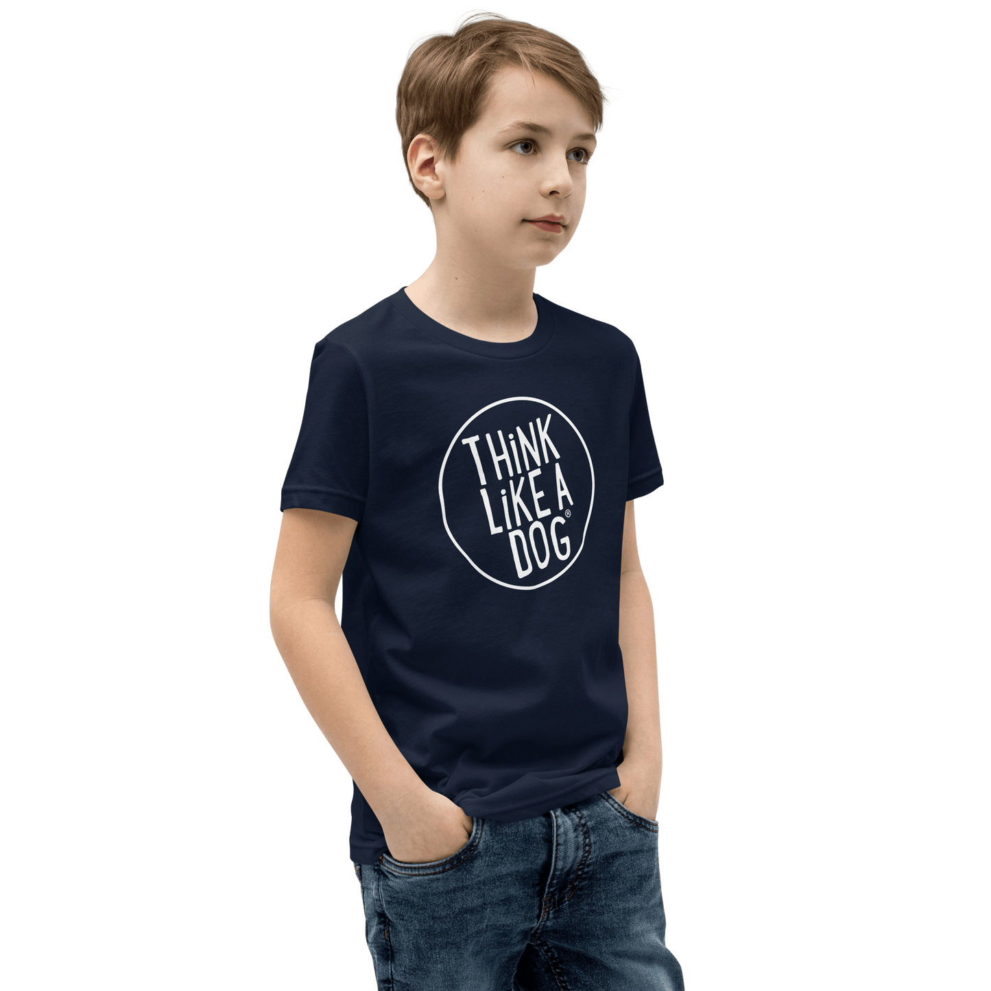 A young dog-loving kid stands with hands in pockets, wearing a Kids' Short Sleeve T-Shirt from THiNK LiKE A DOG®, featuring the Think Like a Dog® white logo.