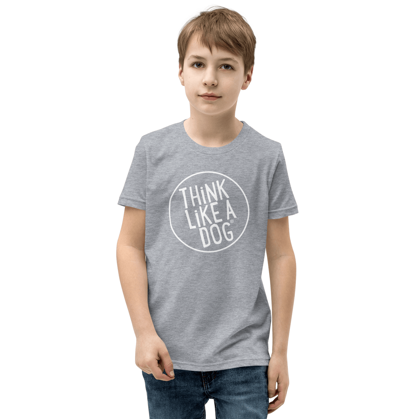 A boy proudly shows off the Kids' Short Sleeve T-Shirt from THiNK LiKE A DOG®, featuring the white Think Like a Dog® logo, set against a black backdrop, capturing the spirit of dog-loving kids.