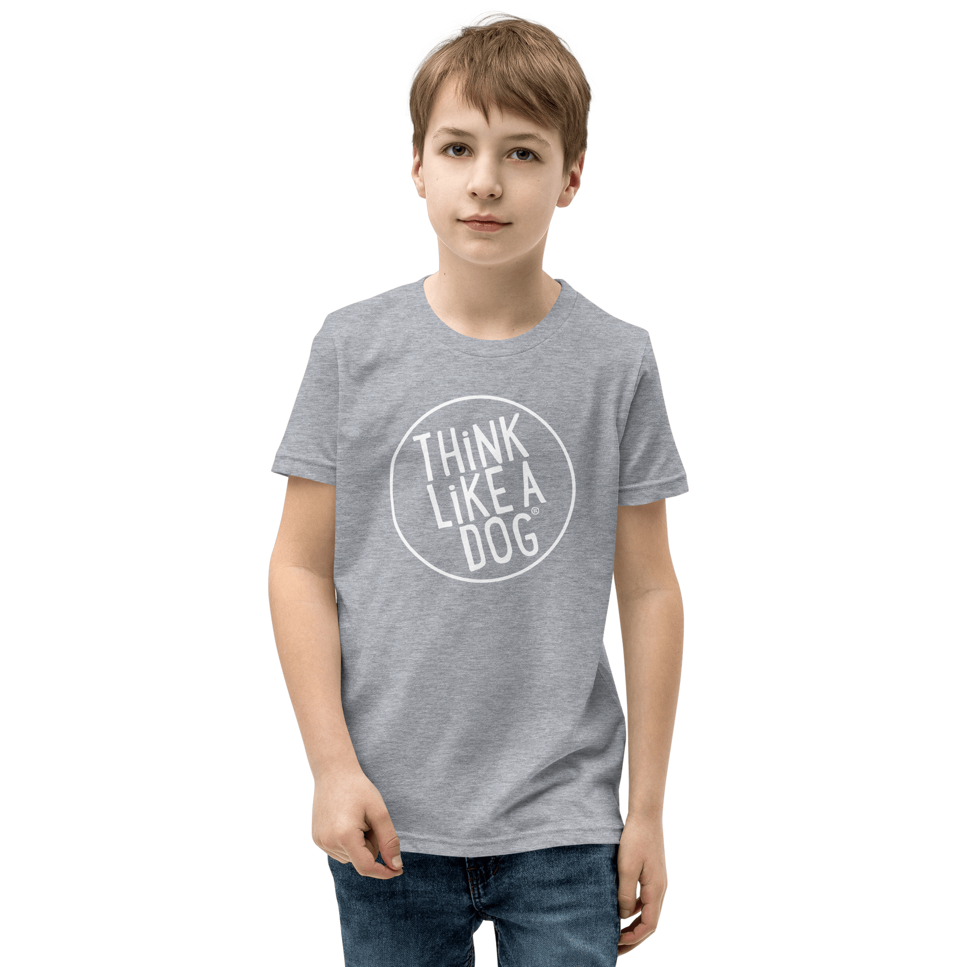 A boy proudly shows off the Kids' Short Sleeve T-Shirt from THiNK LiKE A DOG®, featuring the white Think Like a Dog® logo, set against a black backdrop, capturing the spirit of dog-loving kids.