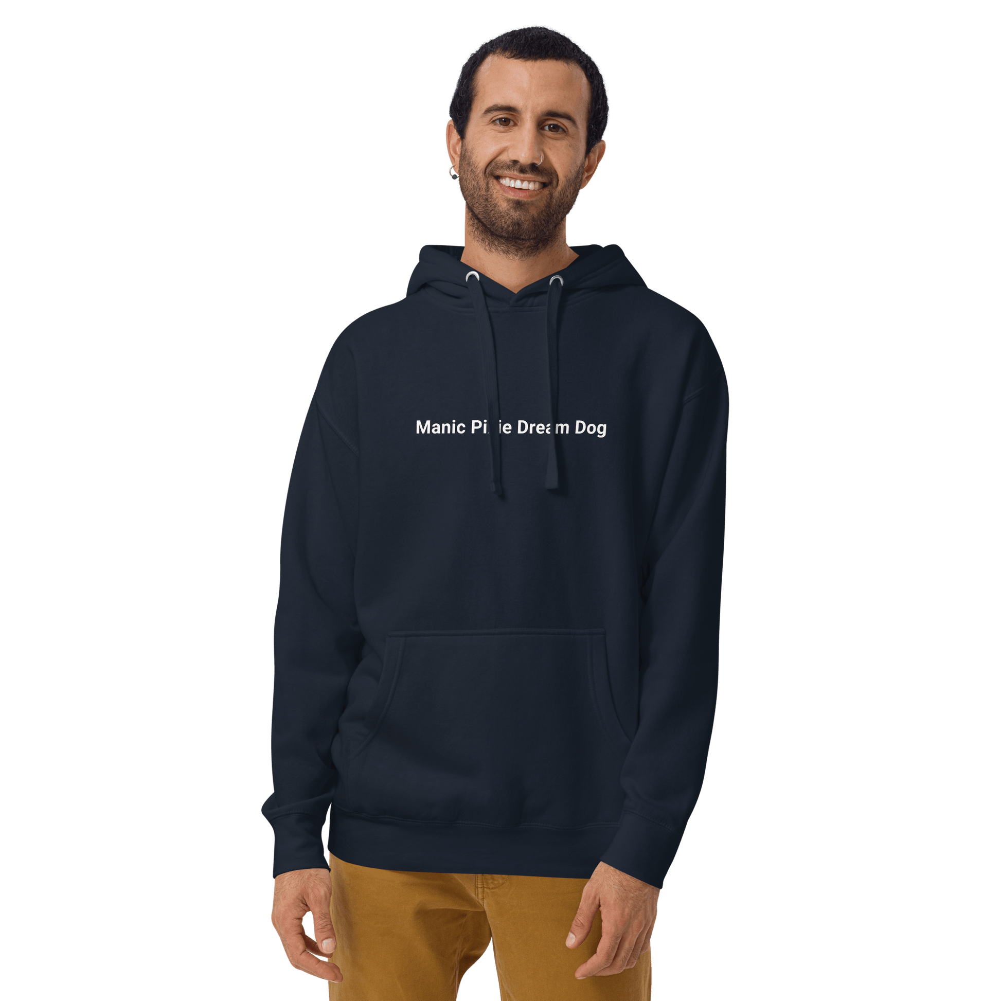 Wearing light brown pants, a person smiles in a dark hoodie with "Manic Pixie Dream Dog" text from THiNK LiKE A DOG® against a black backdrop, highlighting the Manic Pixie Dream Dog Hoodie—ideal minimalist apparel for dog lovers.