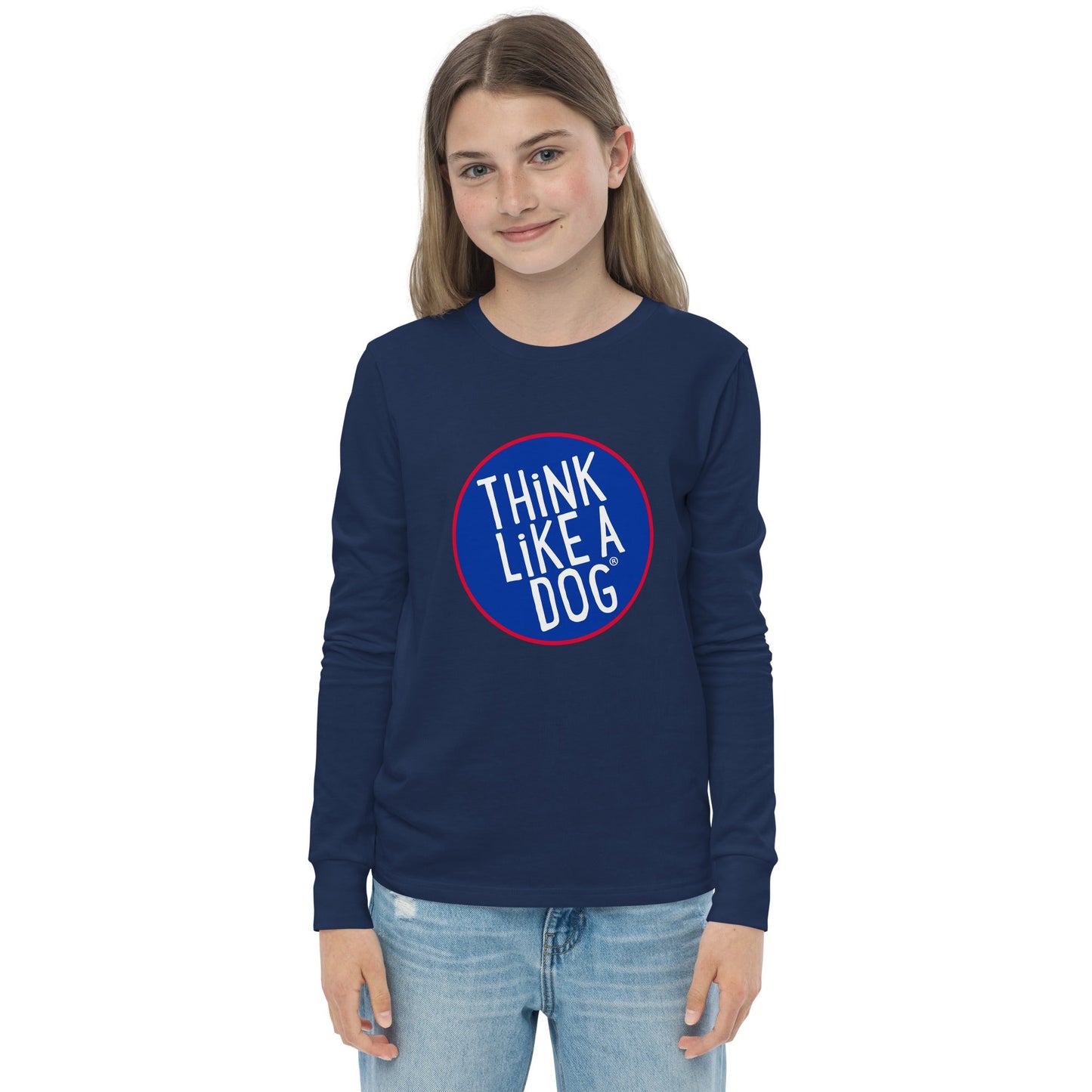 A young person is wearing a Kids' Think Like A Dog NASA-Style Long Sleeve Tee from THiNK LiKE A DOG®, crafted with high-quality soft fabric. The navy blue shirt, part of the Cute and Quirky Dog Apparel line, features "THINK LIKE A DOG" in a circular emblem on the front. They are standing and smiling with their hands at their sides.