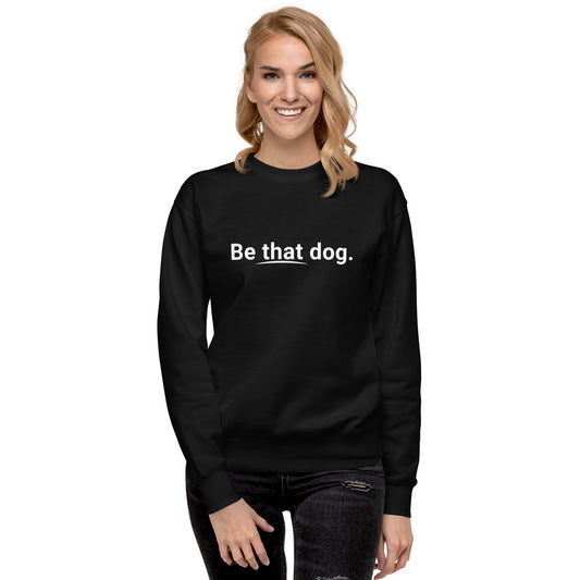 A blond woman smiles at the camera in a cozy unisex black "Be That Dog Sweatshirt – Simple Statement" by THiNK LiKE A DOG®, with “Be that dog.” in white—a perfect gift for dog lovers.