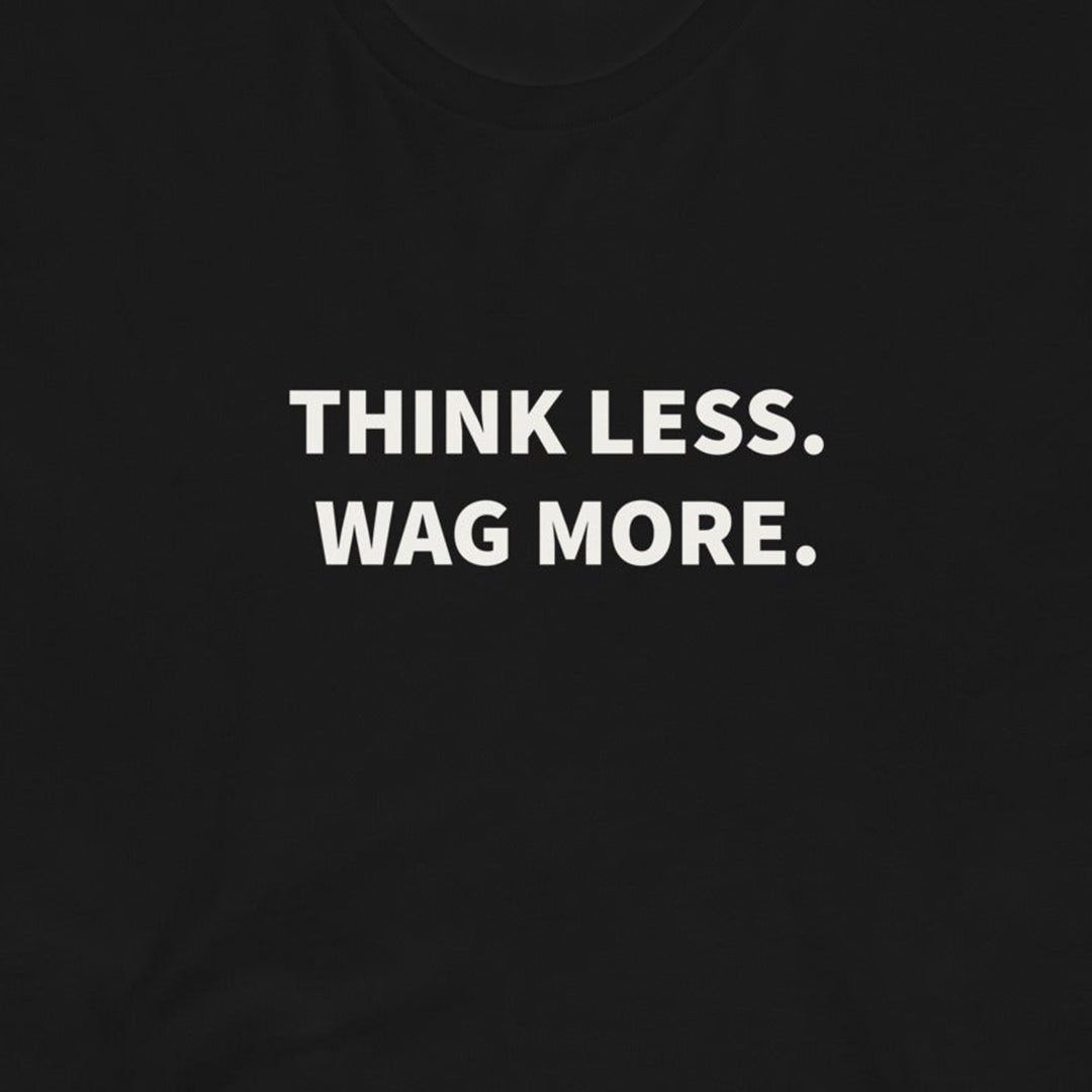 The Think Less. Wag More. Dog Lover Tee by THiNK LiKE A DOG® features white text on a black shirt—perfect for any dog lover’s collection or proud dog parent!.