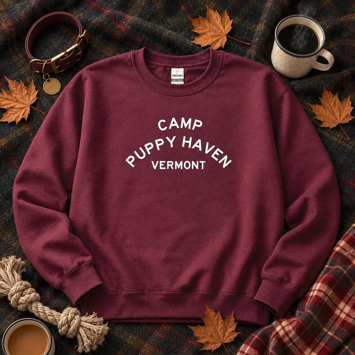 Camp Puppy Haven Vermont Crewneck in Maroon on a plaid blanket with fallen maple leaves, a dog collar, rope toy, and two mugs of coffee