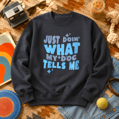 Navy "Just Doin' What My Dog Tells Me" sweatshirt on a southwestern rug with a vintage Polaroid camera, sunglasses, iced coffee, rope toy, tennis ball, denim, and a leather dog collar with bone-shaped tag