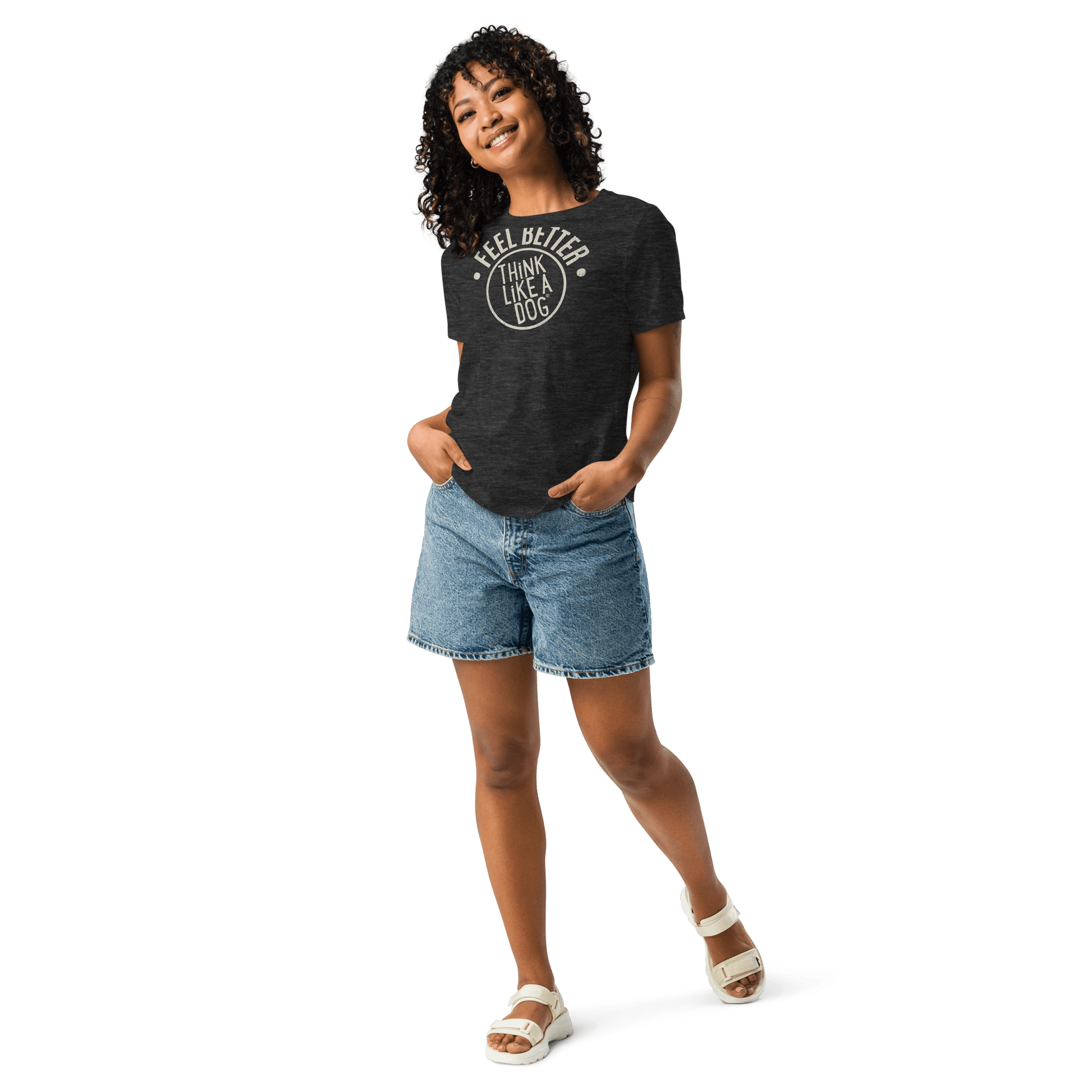 Smiling with hands in pockets, the person sports jean shorts, white sandals, and a THiNK LiKE A DOG® Feel Better Women's T-Shirt—an ultra-soft black top with "I Feel Better After I Lick A Dog," perfect for dog moms and animal enthusiasts.