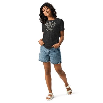 Smiling with hands in pockets, the person sports jean shorts, white sandals, and a THiNK LiKE A DOG® Feel Better Women's T-Shirt—an ultra-soft black top with "I Feel Better After I Lick A Dog," perfect for dog moms and animal enthusiasts.