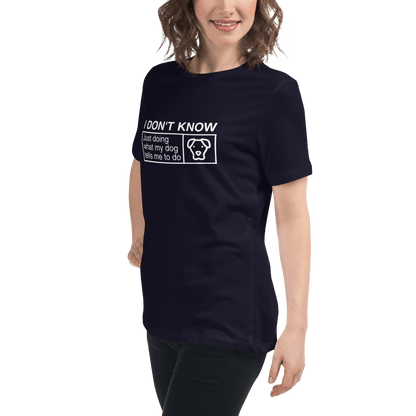 A person wears a black THiNK LiKE A DOG® women’s tee that says, "Just Doing What My Dog Tells Me," featuring a dog image. This funny shirt humorously captures the bond between pet and owner, perfect for any devoted dog mom.