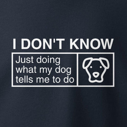 A graphic with white text on a dark background reads: "I Don’t Know, Just Doing What My Dog Tells Me To Do," accompanied by an outline of a dog's face—a perfect example of cute and quirky dog apparel from THiNK LiKE A DOG®'s Humorous Dog Hoodie collection.