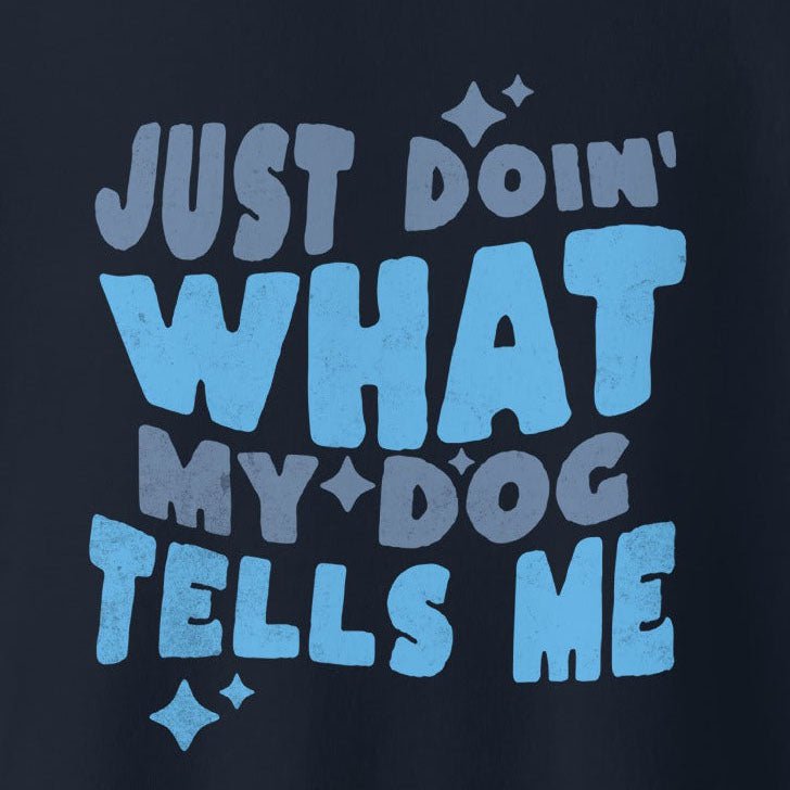 Text reads: "Just doin' what my dog tells me" in a playful font with different shades of blue and white, perfect for the THiNK LiKE A DOG® Quirky Dog Lover Sweatshirt – ‘Just Doing What My Dog Tells Me’ Design.