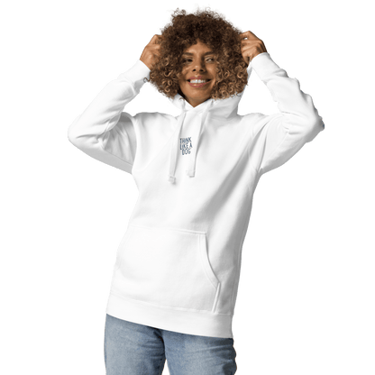 A smiling person in a THiNK LiKE A DOG® Think Like a Dog Hoodie — Everyday Comfort, featuring "Think Like a Dog" text on the chest, holds the hood while standing against a plain light background.
