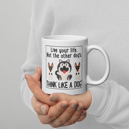 A person holding a THiNK LiKE A DOG® White glossy Mug Live Your Life. Not The Other Dog's with a cartoon of two dogs and the phrase "live your life, not the other dogs. think like a dog" printed on it.
