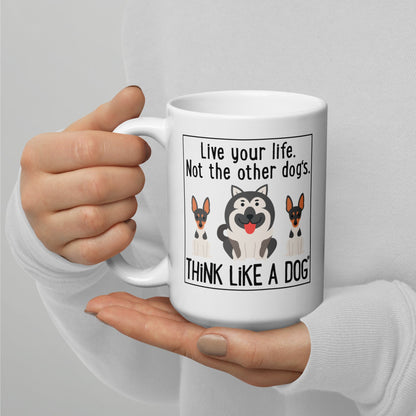 A person holding a THiNK LiKE A DOG® white glossy mug with cartoon dogs and the phrase "live your life, not the other dog's. Think like a dog.