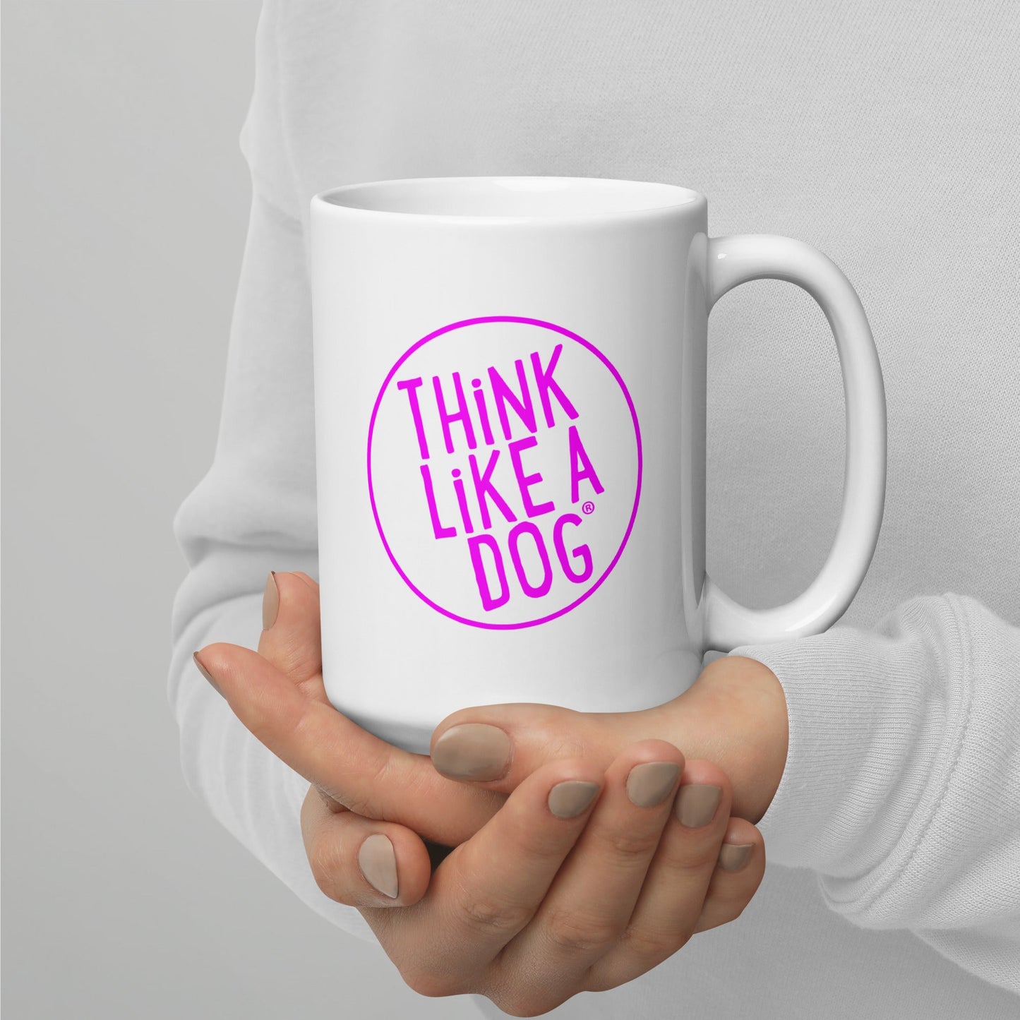 A person holding a White Glossy Mug Magenta THiNK LiKE A DOG® Logo with the phrase "THiNK LiKE A DOG®" inside a pink circle.