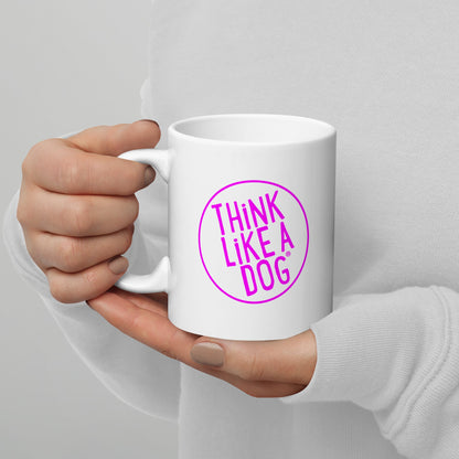 A person holding a White Glossy Mug Magenta THiNK LiKE A DOG® Logo with the text "THiNK LiKE A DOG®" in a pink circle.