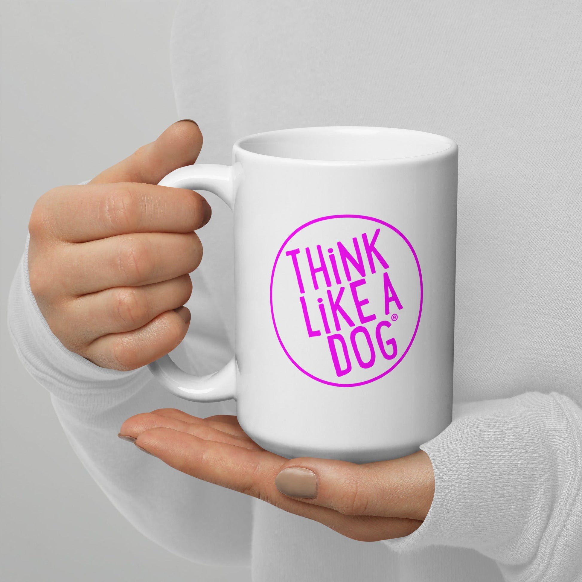 Person holding a White Glossy Mug Magenta THiNK LiKE A DOG® Logo with the text "THiNK LiKE A DOG®" printed on it.