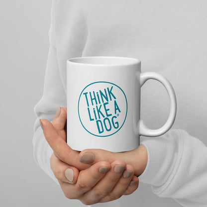 Person holding a white glossy mug with the text "THiNK LiKE A DOG®" printed on it for dog lovers.